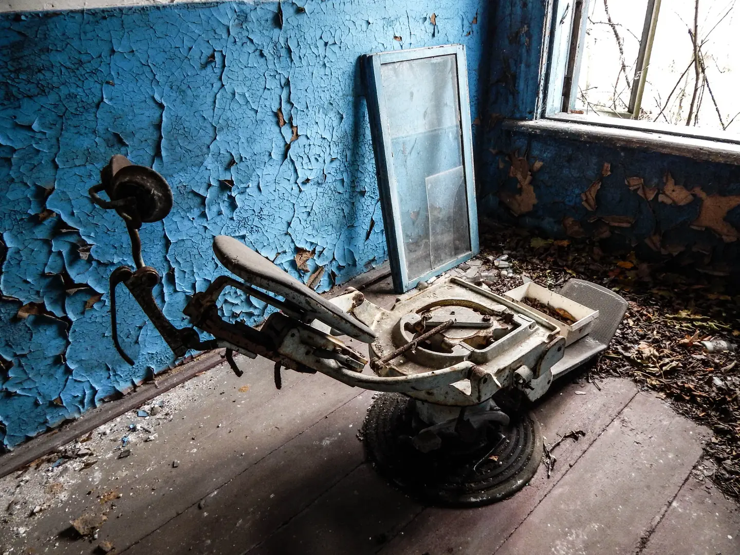 An abandoned dentist’s chair beside peeling blue walls