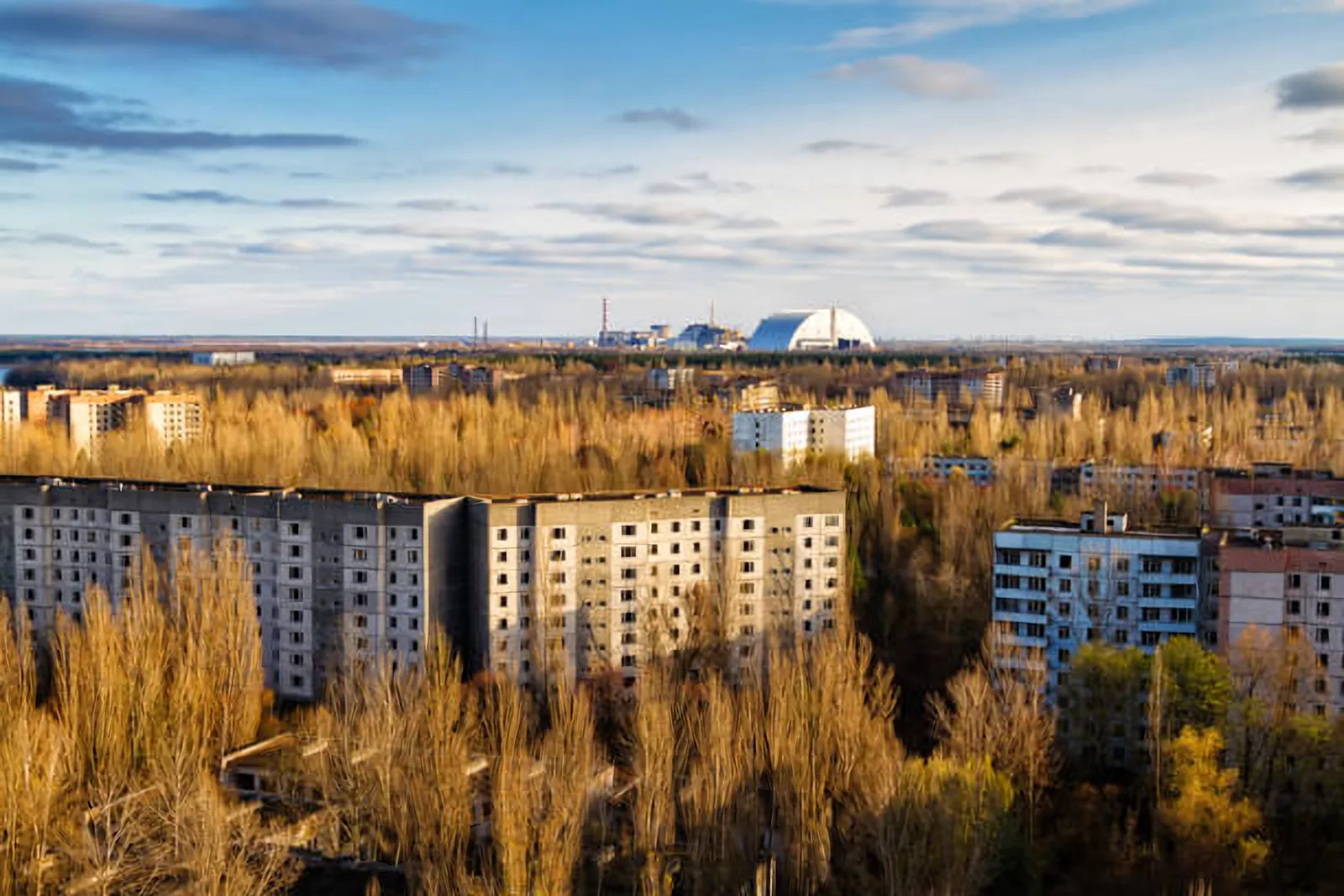 Abandoned apartment blocks in Pripyat with the Chernobyl power plant’s New Safe Confinement on the horizon